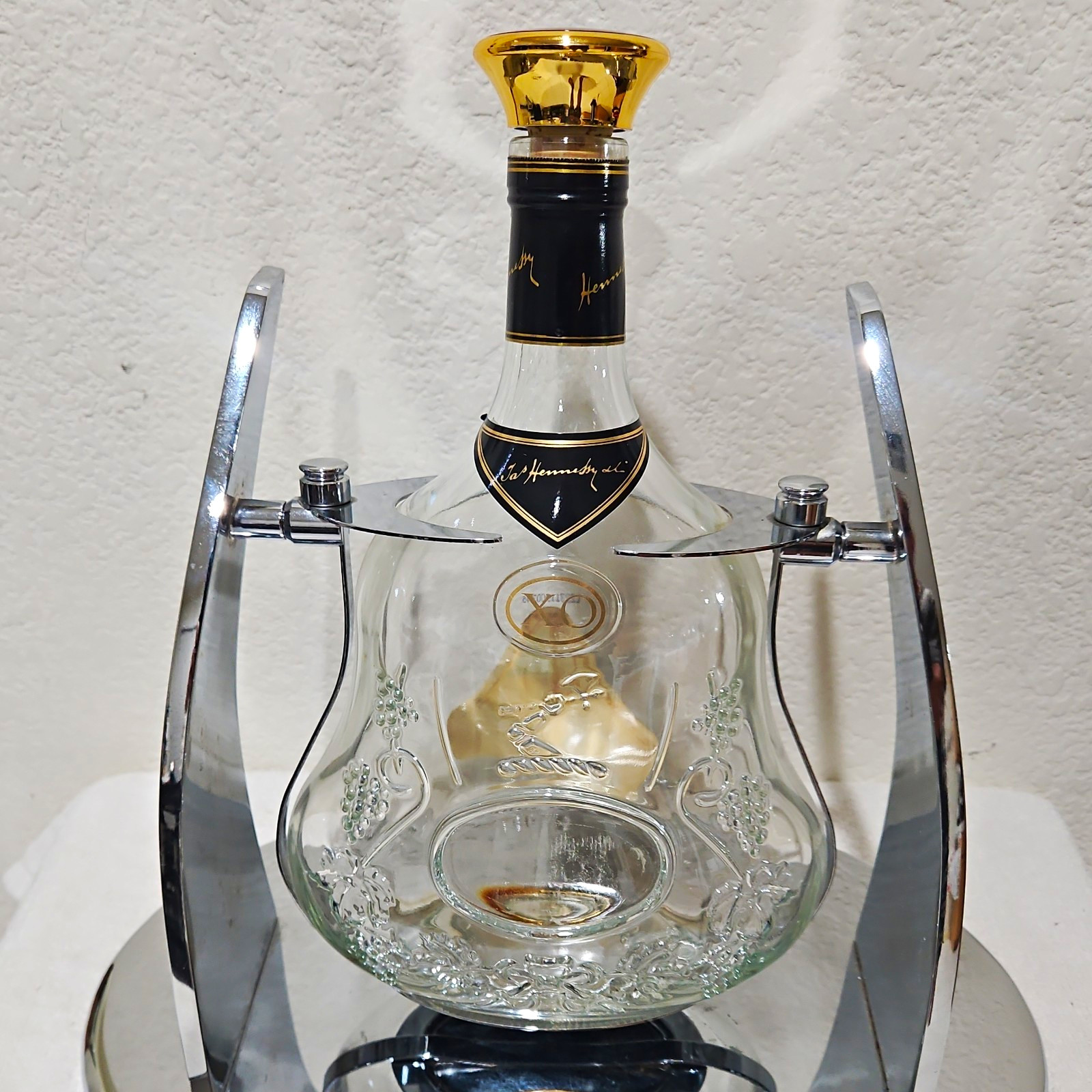 Hennessy XO Cognac. Empty Bottle Clear Glass w/ Chrome Cradle Display Stand.