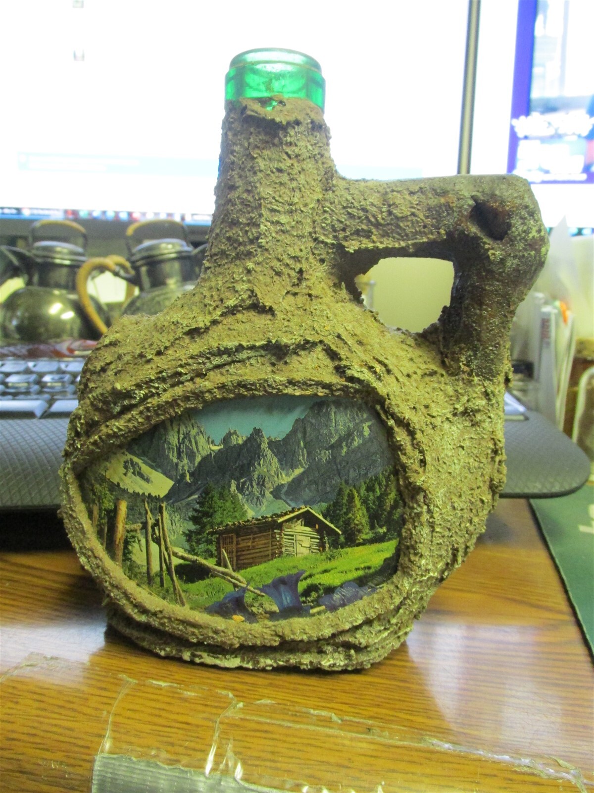 "Bark" covered, handled wine or liquor bottle w/ picture of cabin in hills