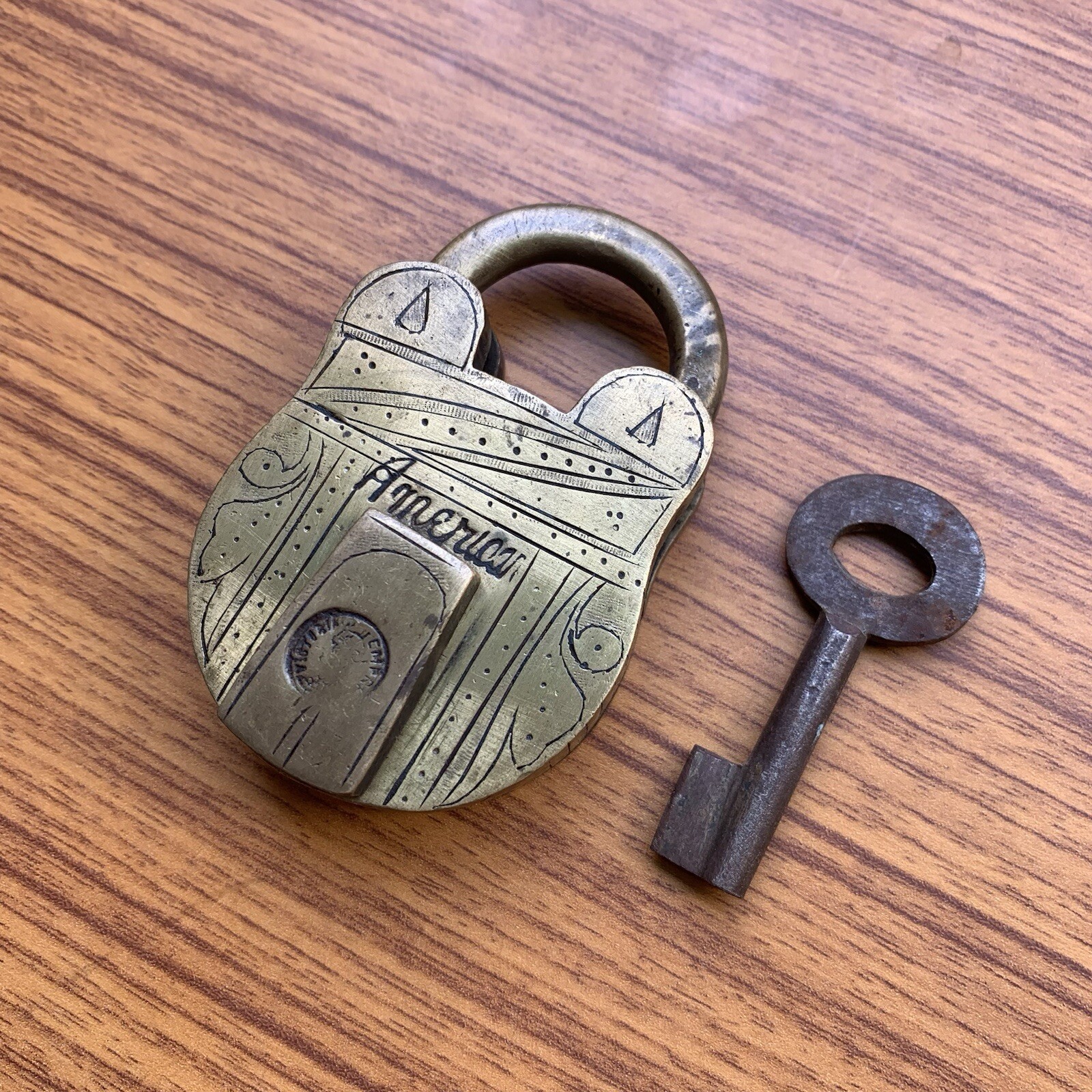 An old or antique brass padlock or lock with key carving on both sides.