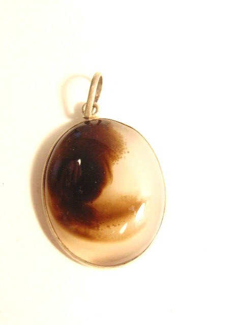 translucent brown and milky color gemstone pendant in silver colored setting