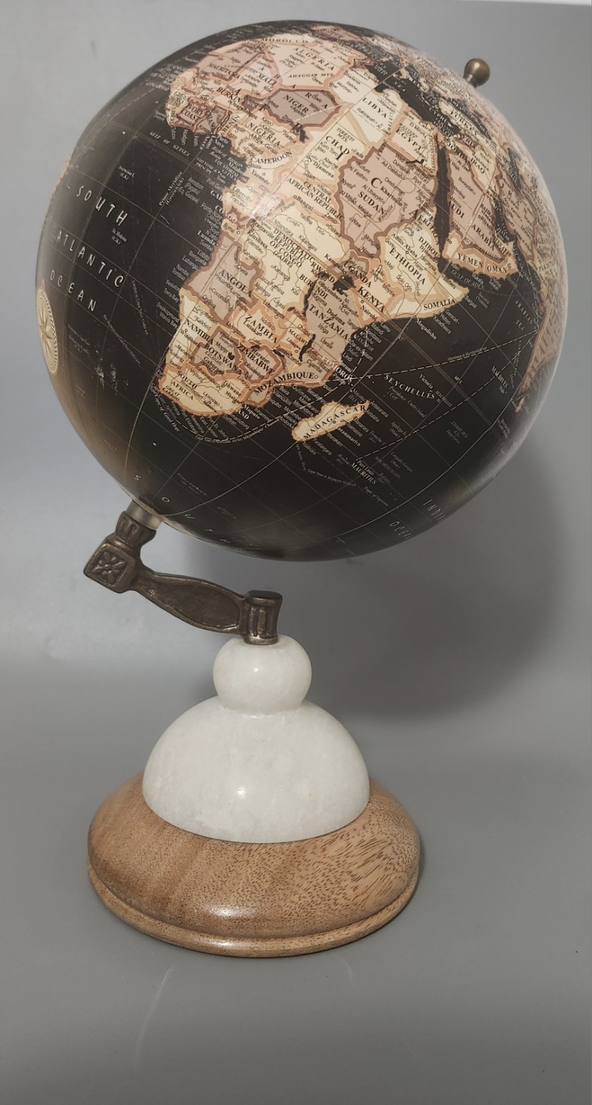 Mid-Century Modern style black desk globe with a wood and white stone stand