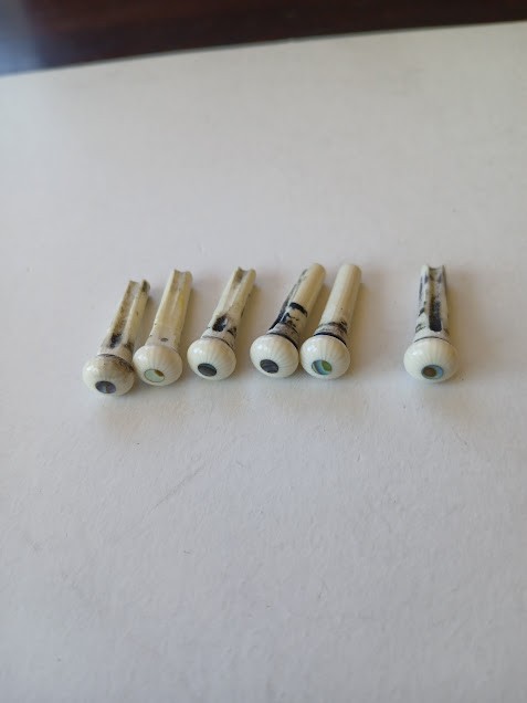 Set of 6 used slotted Casein acoustic guitar bridge pins with mop dot.