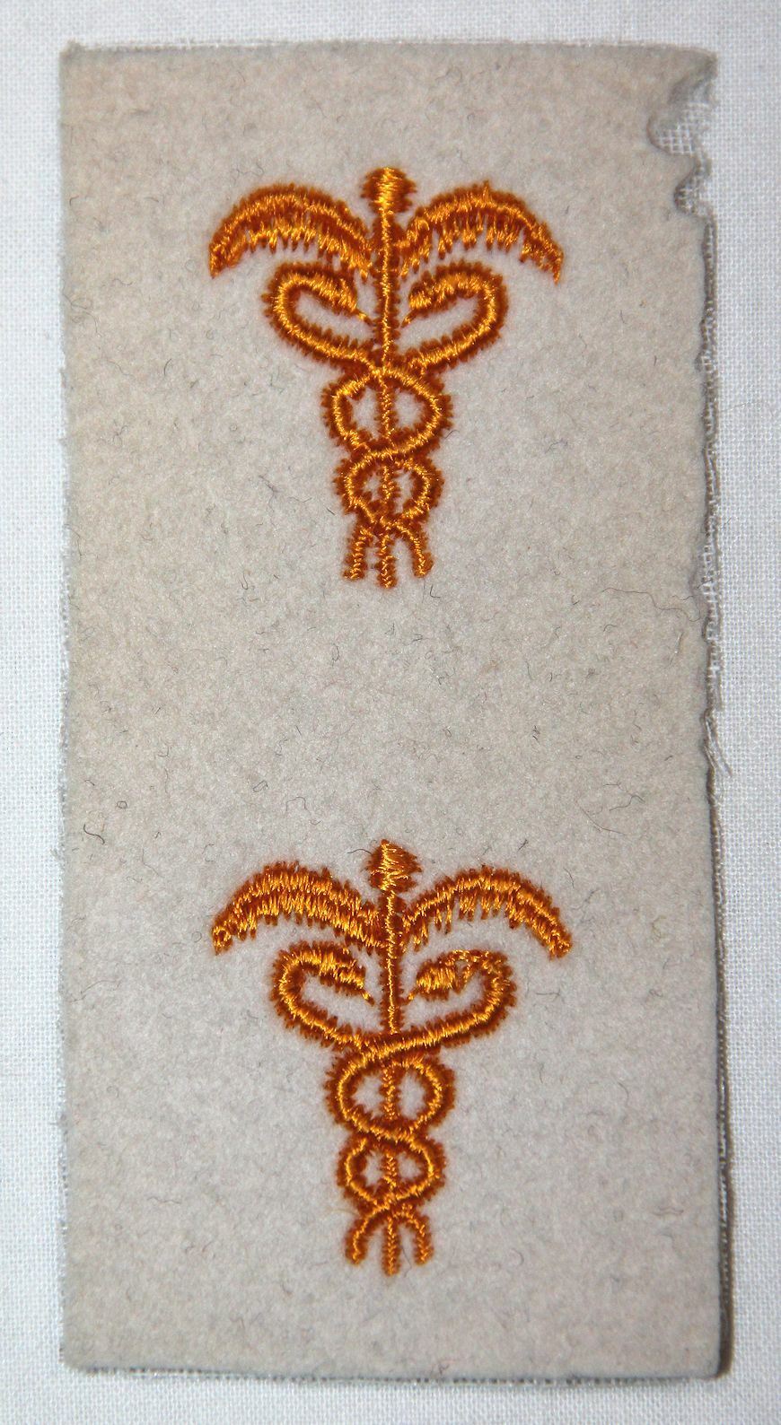 UNISSUED, ORIGINAL WWII MEDICAL OFFICERS BRANCH INSIGNIA ON WHITE WOOL
