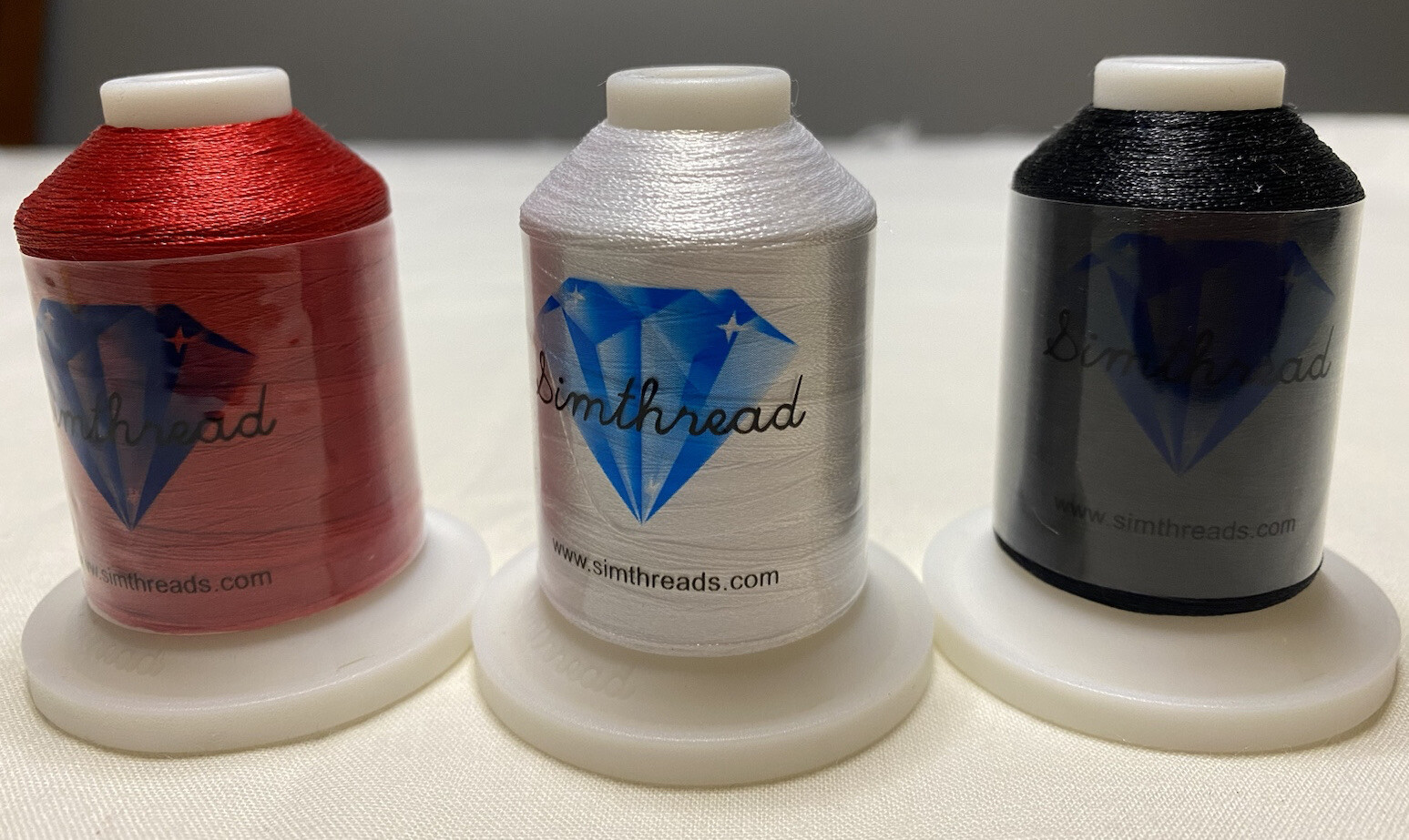 White, black and red spools (1 each) of new Simthread embriodery thread