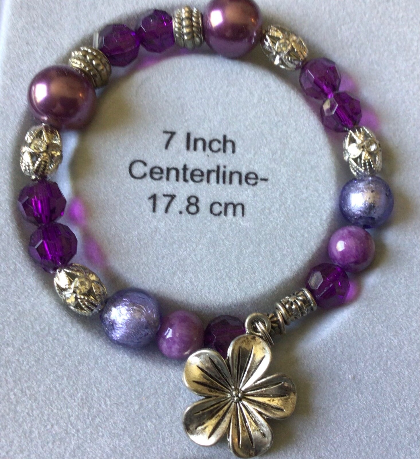 7" bracelet, handmade with purple hues and a flower charm, made in the USA