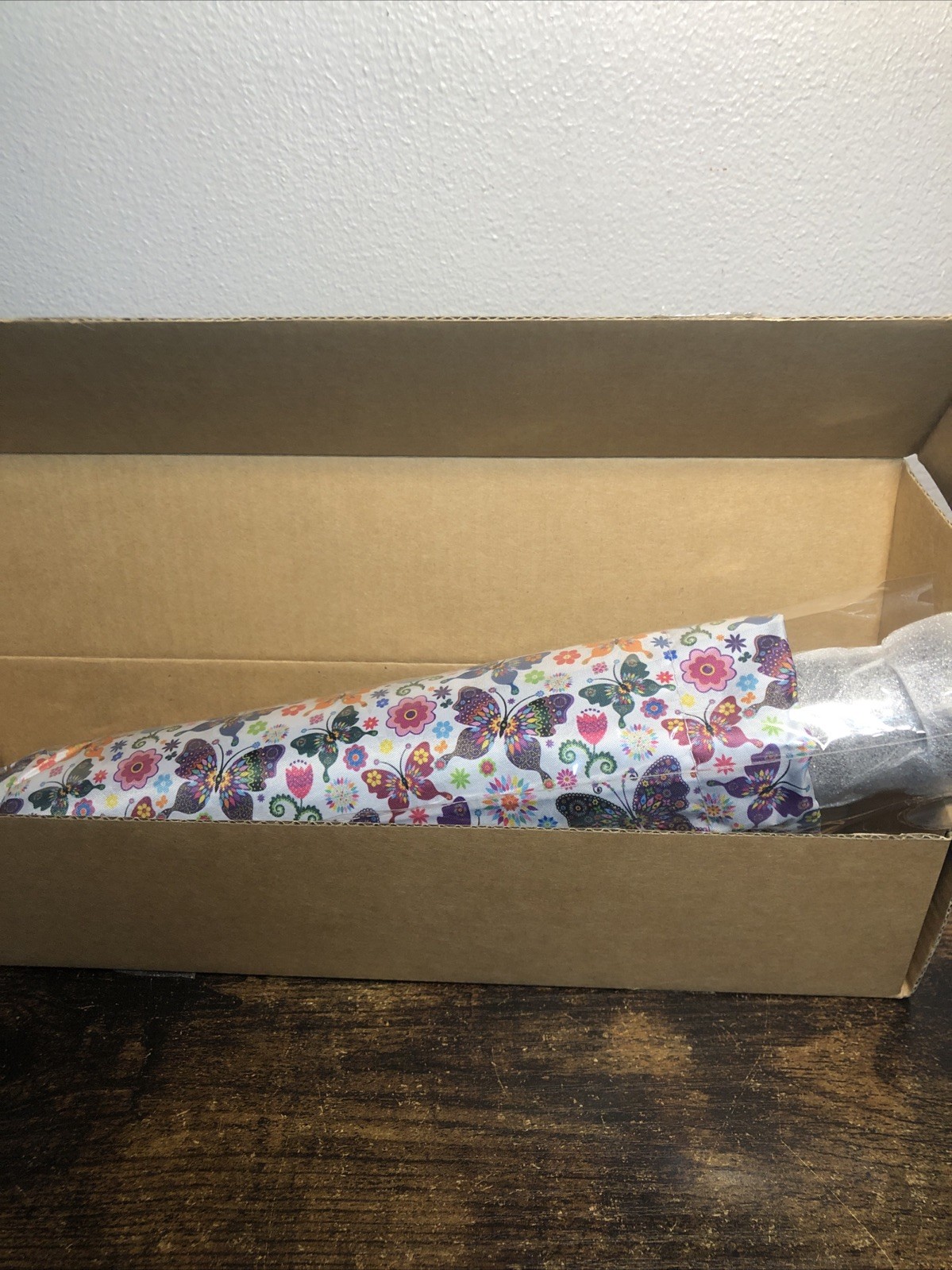 A portable travel umbrella for rain or shine with butterflies and flowers
