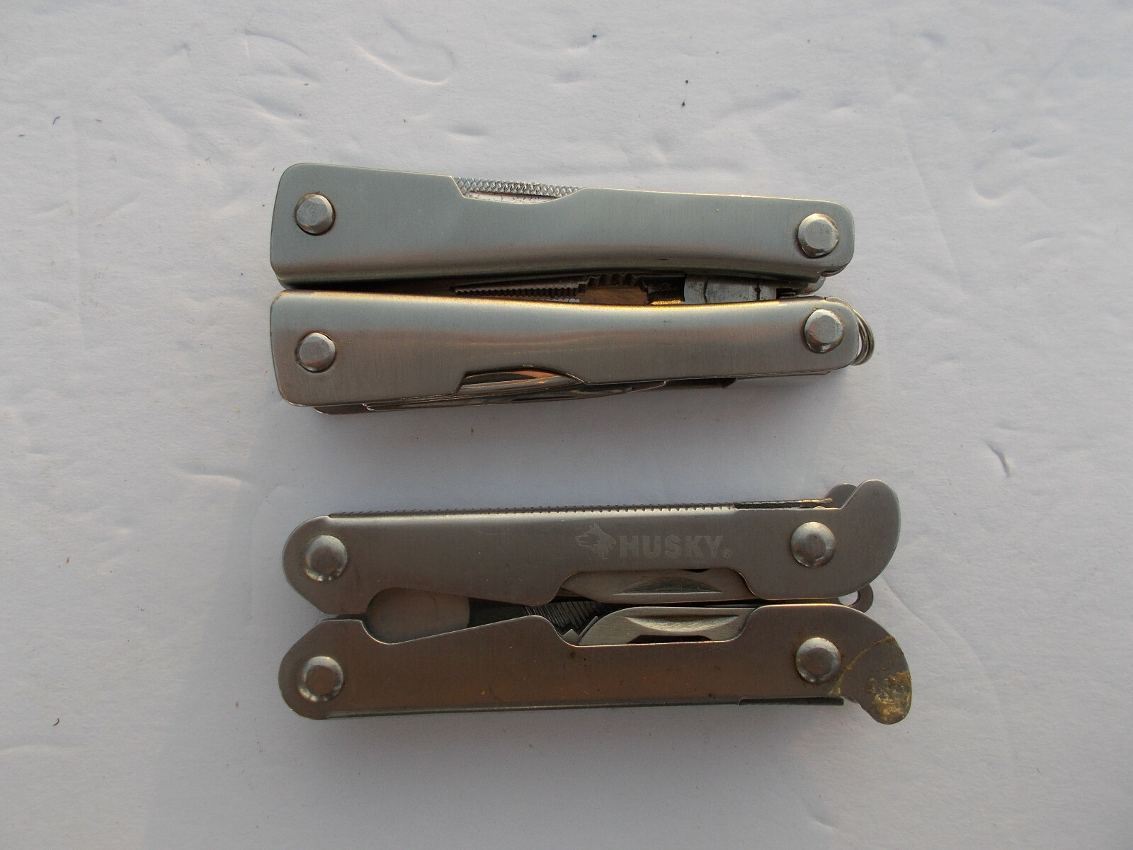 Lot of (2) multi tools - 1 Husky silver color and 1 unbranded silver color