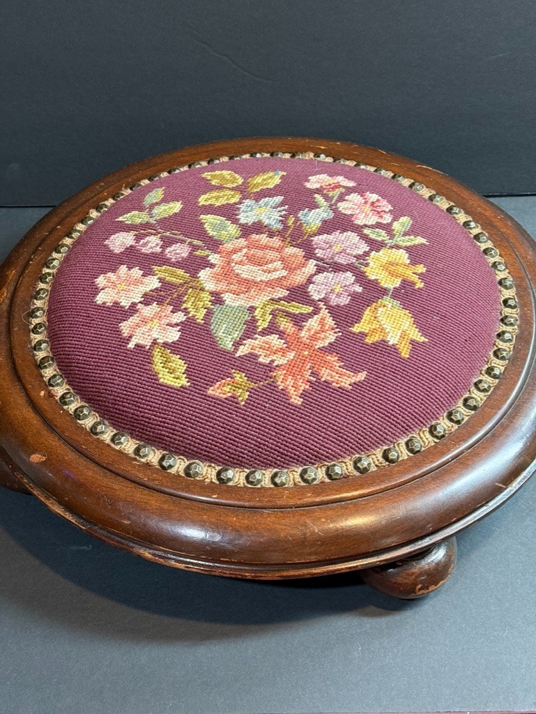 Victorian-era style wood round footstool with a floral needlepoint