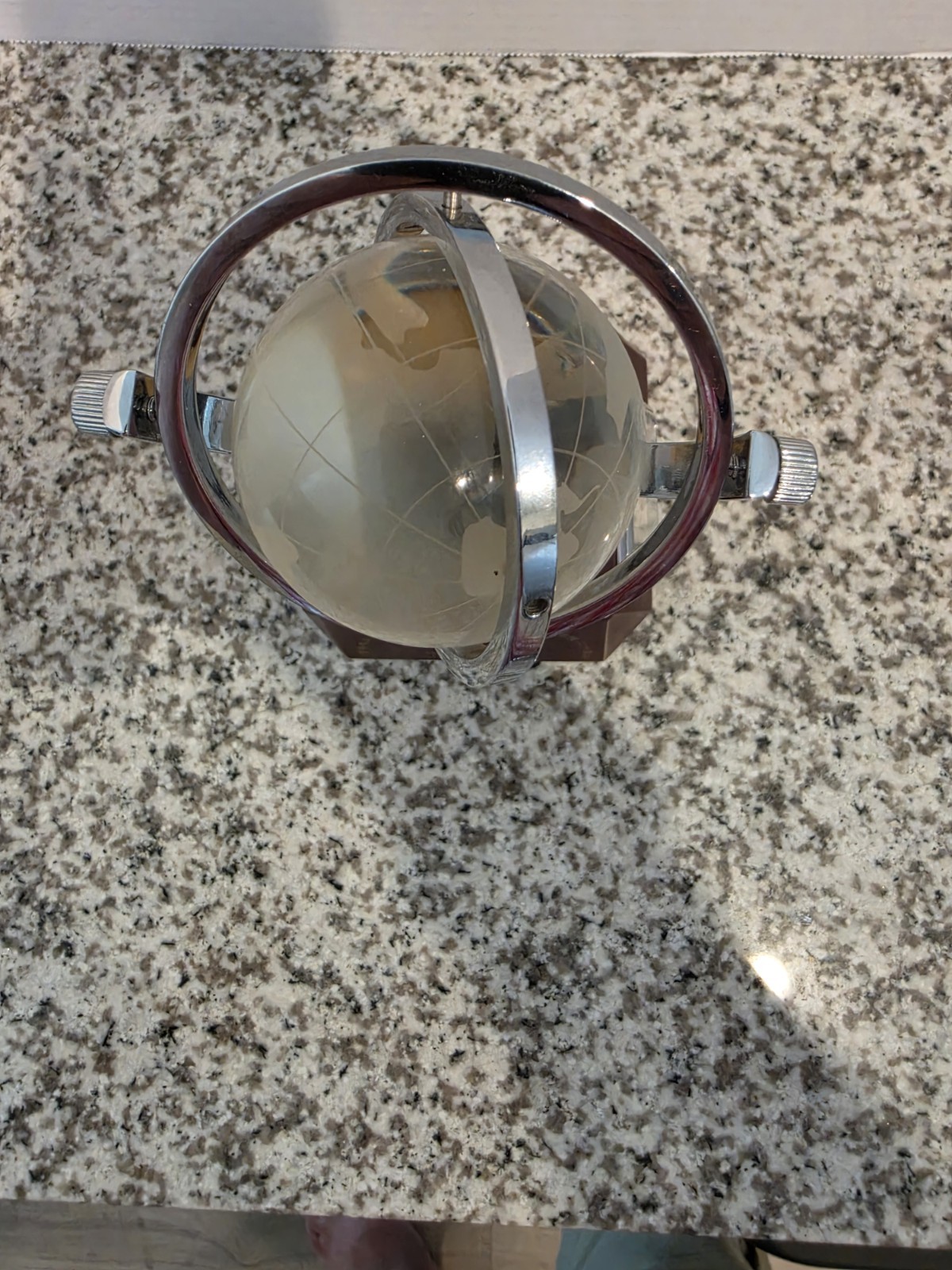 globe featuring a rotating globe set above a gold-colored handshake sculpture