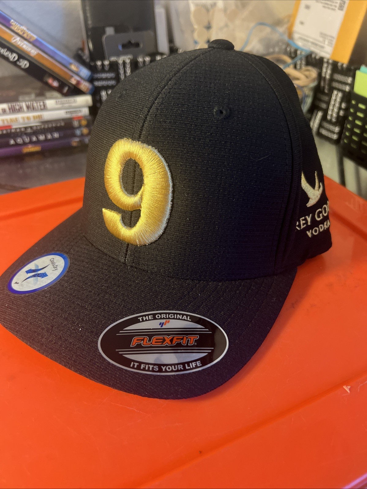 Flexfit Cool & Dry hat with a gold embroidered "9" and a Grey Goose Vodka logo.