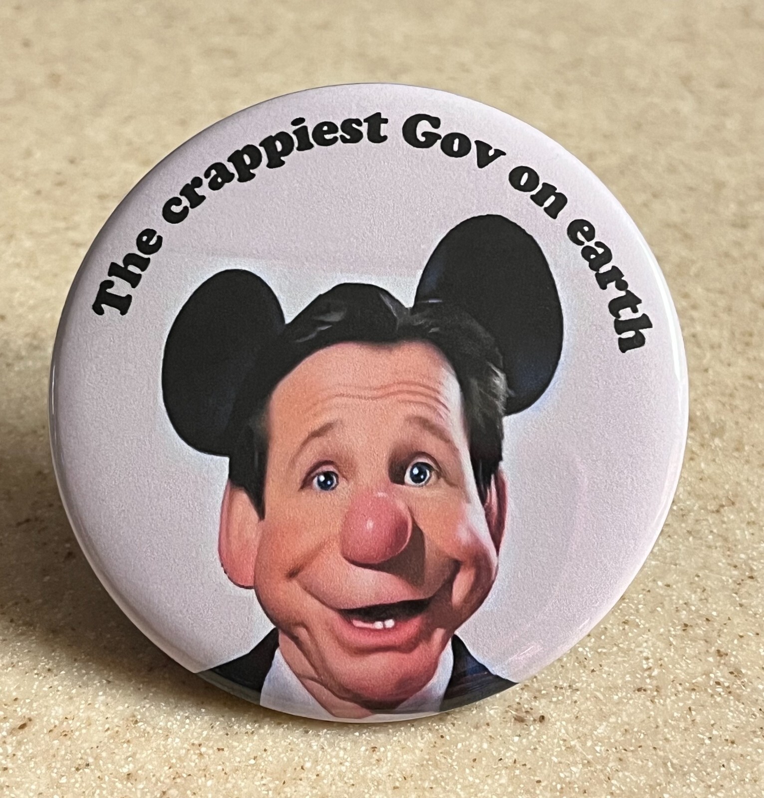 Anti-Ron DeSantis Pin-Back Button 2 1/4 inch "The crappiest Gov on earth"