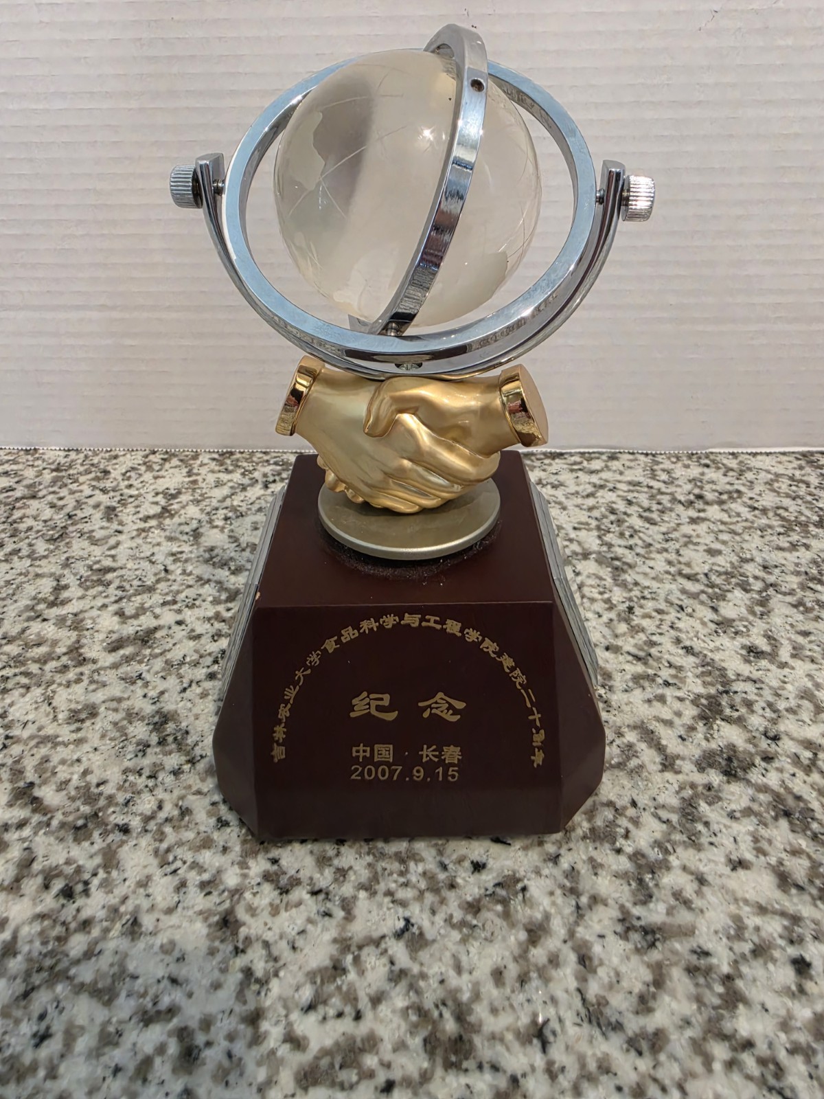 globe featuring a rotating globe set above a gold-colored handshake sculpture