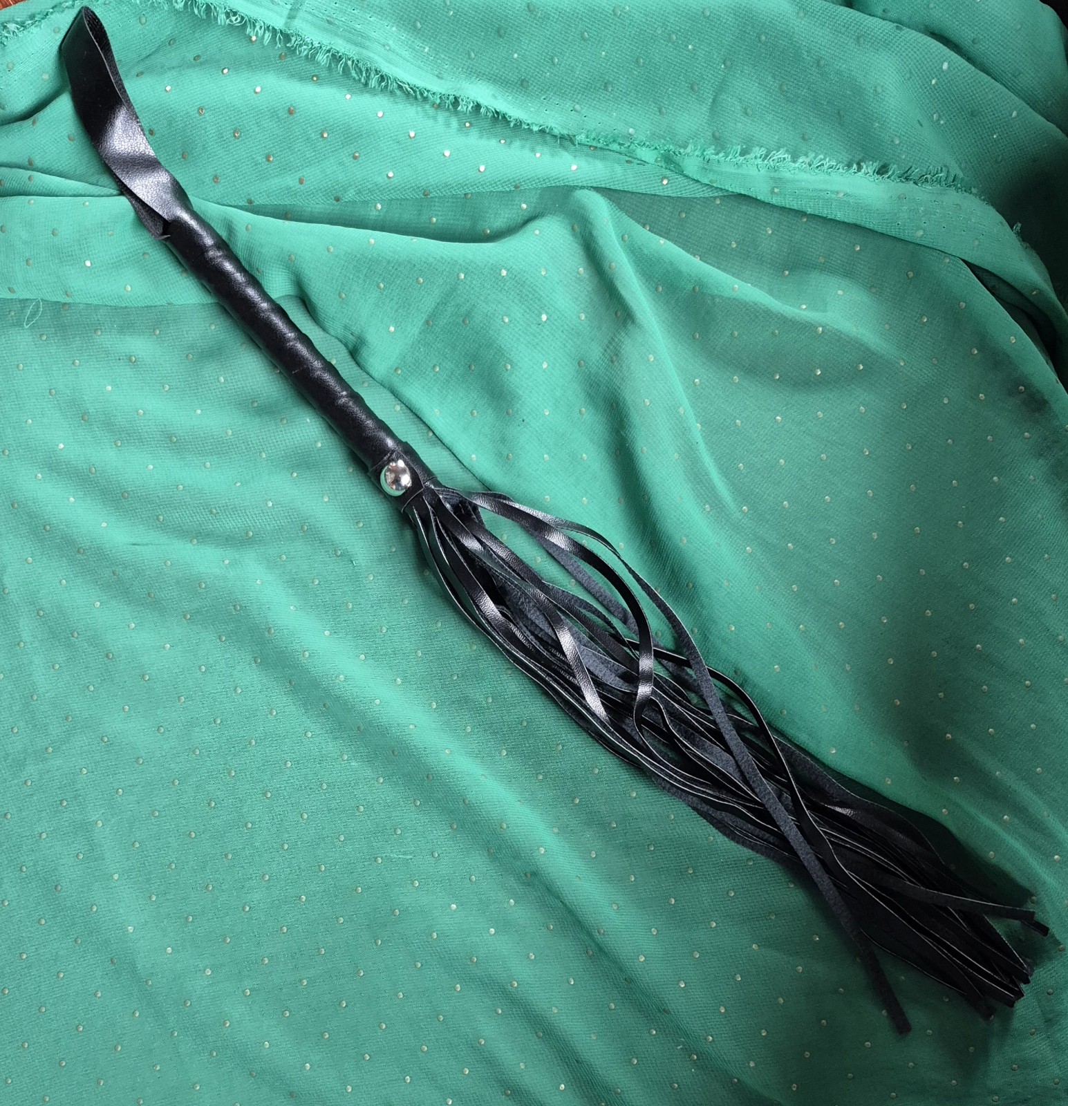 black faux leather flogger whip, often used for equestrian purposes or costume
