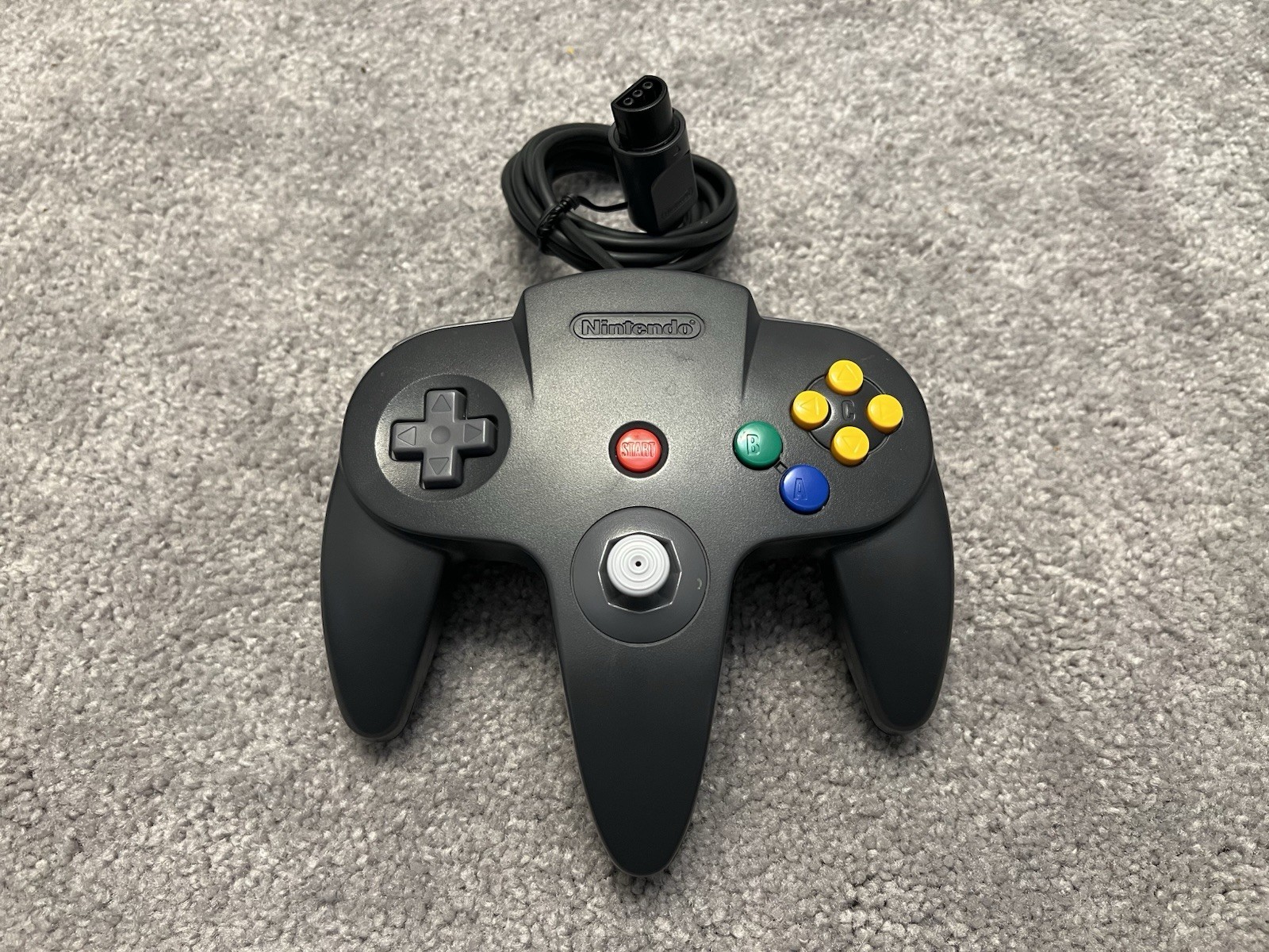 Nintendo 64 with black controller, AV cables, and power supply.
