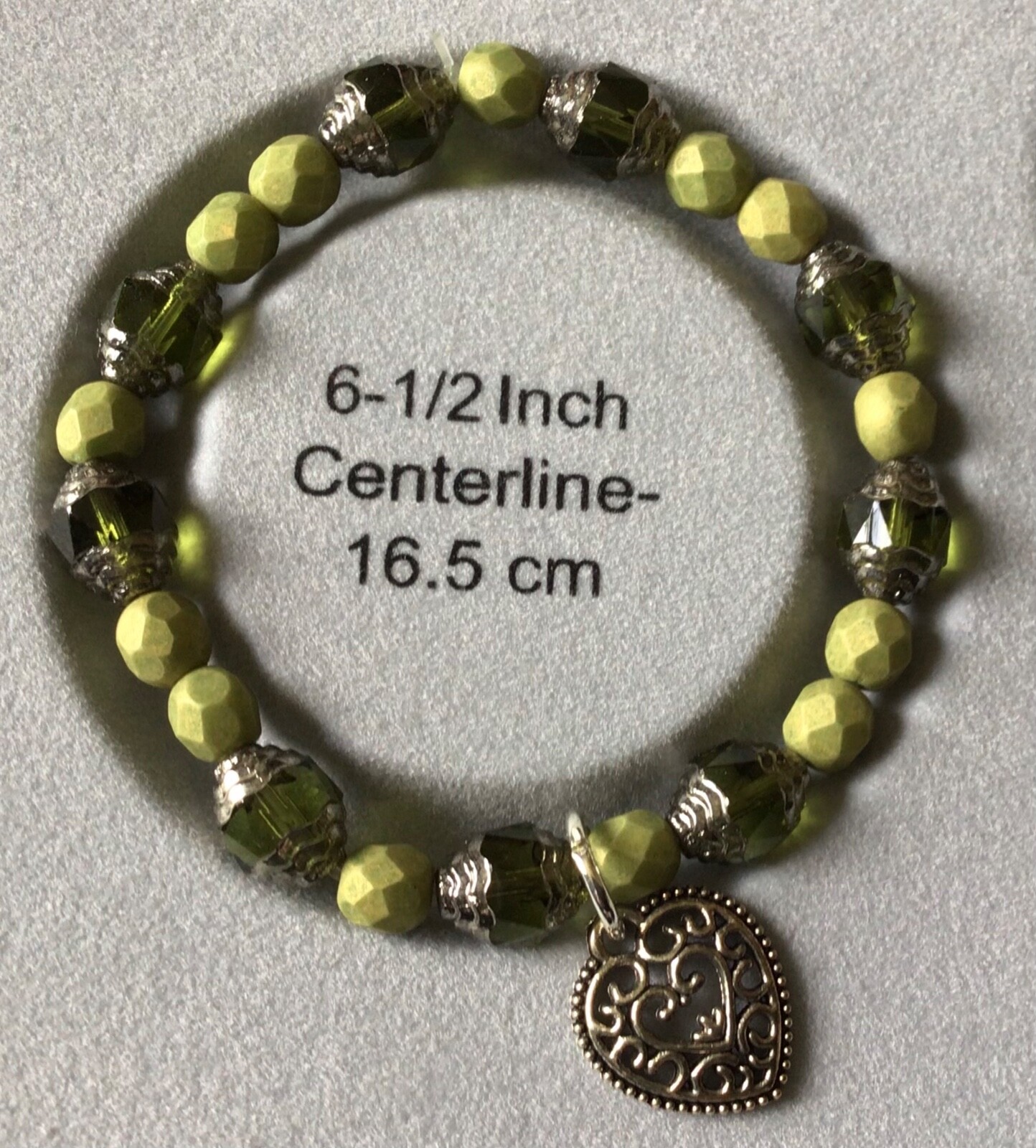 6.5”stretch bracelet with shades of green and a heart charm, Made in the USA