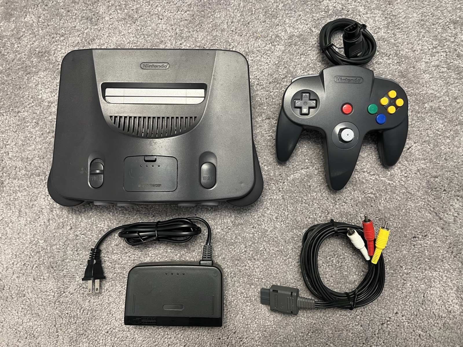 Nintendo 64 with black controller, AV cables, and power supply.