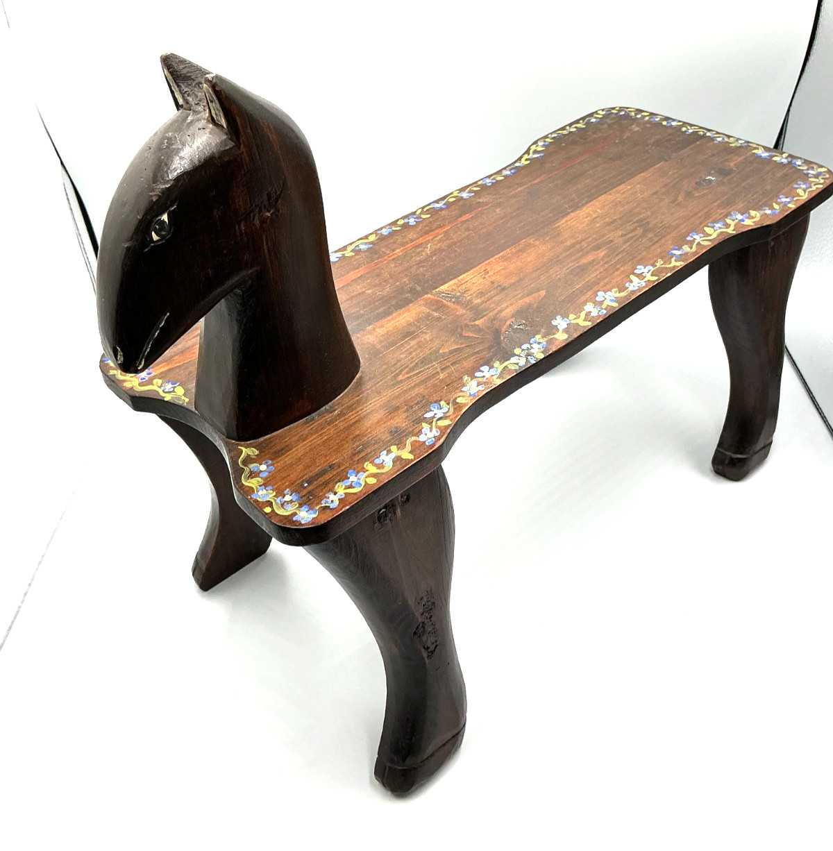 carved wooden bench with painted floral motifs and horse head