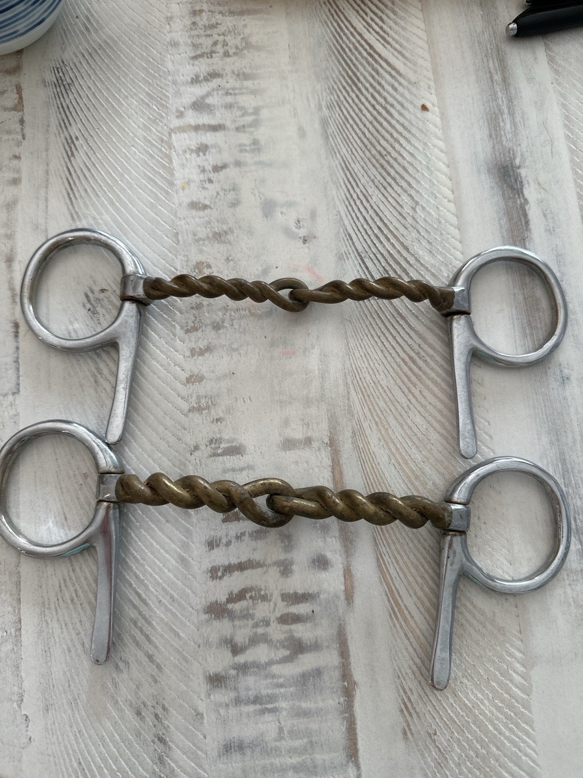 Pair of 5.5” twisted wire comfort snaffle driving bits with half cheek design.