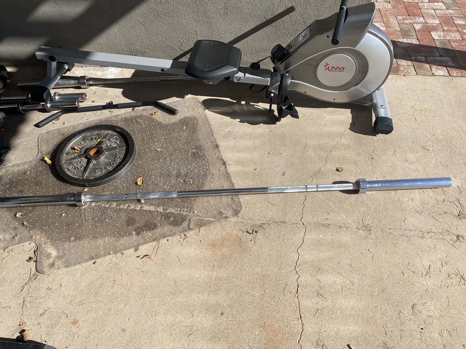 Squat Rack With Bench, Weights, Two Barbells, And A Rowing Machine