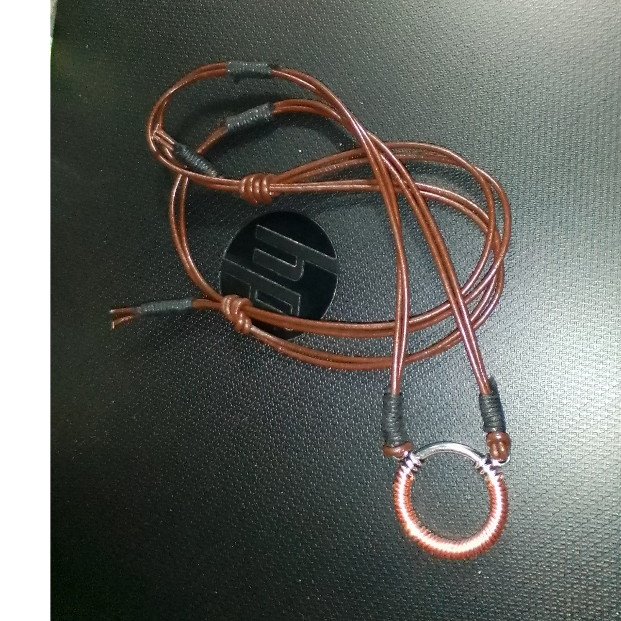 Silver round pendant wrapped in copper with a brown leather lace necklace adjust