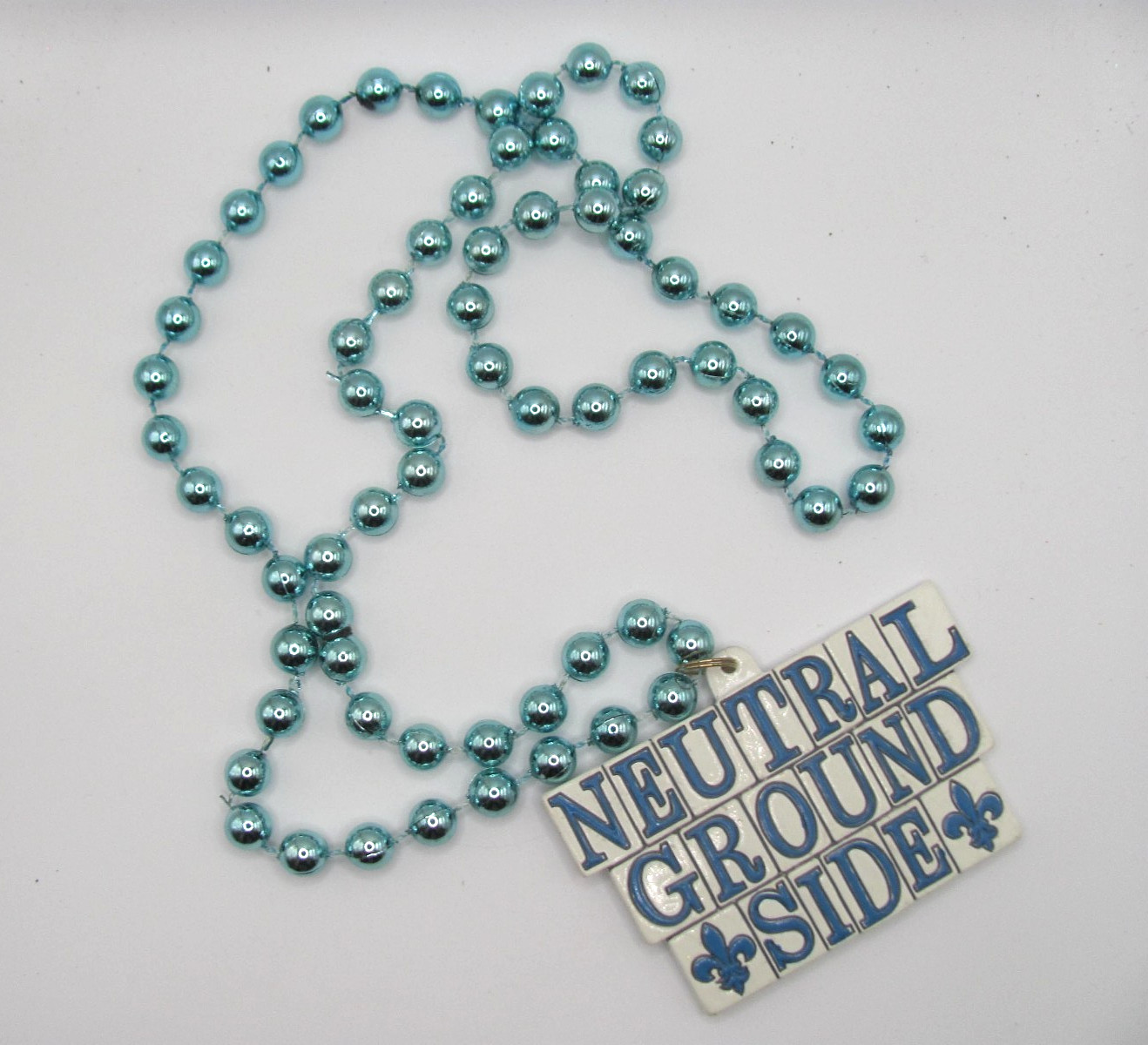 "NEUTRAL GROUND SIDE" POLYSTONE EMBLEM ON A METALLIC BLUE MARDI GRAS BEAD