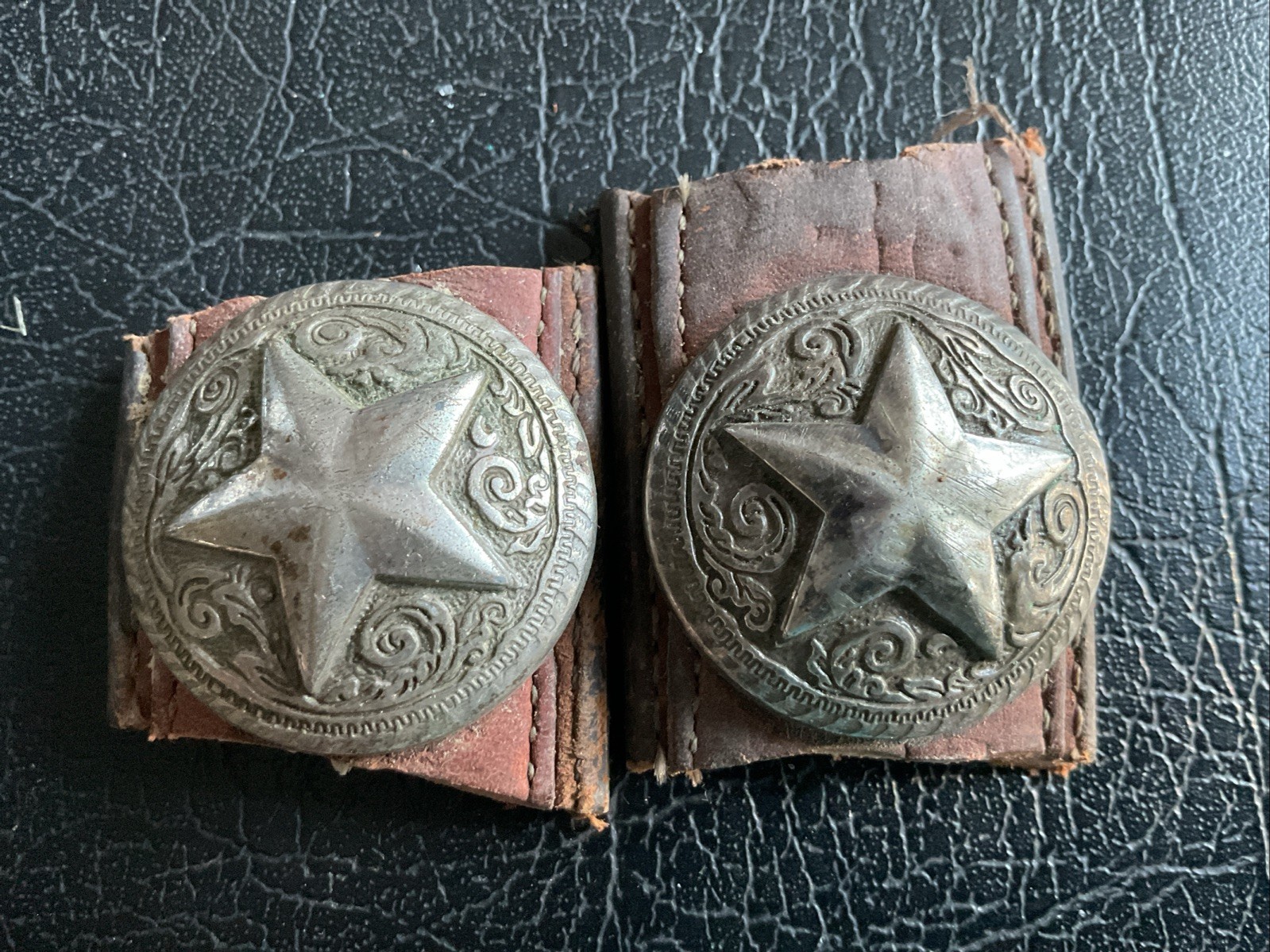 A silver-toned metal concho with a Texas star design on leather.